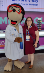 woman with glasses standing next to the ACS mole mascot at the national meeting